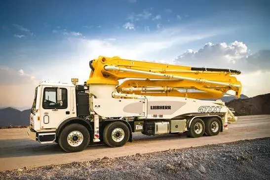 A boom concrete pump truck with its boom folded down, parked on a lot