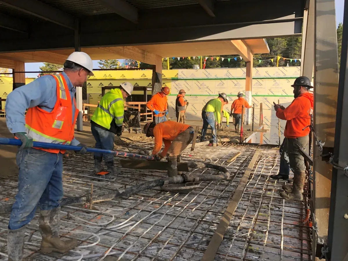 A concrete crew placing and screeding a large slab pour on a reinforced deck at golden hour