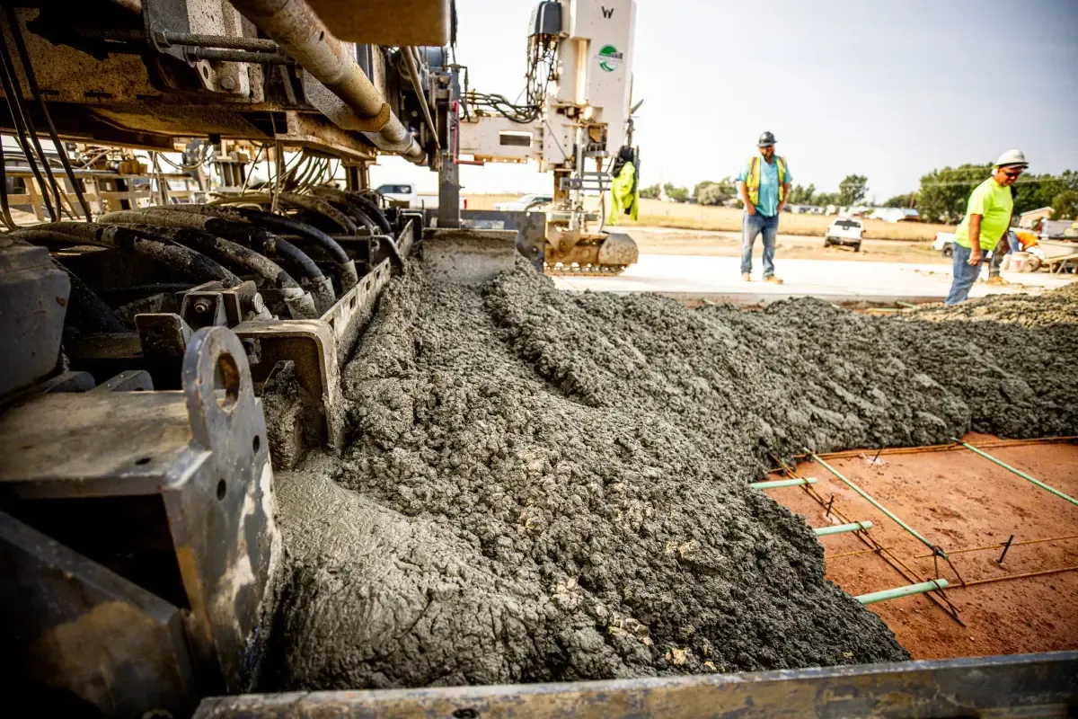 A paving machine spreading concrete over a prepared subgrade as the crew works alongside — concrete contractor insurance in Virginia