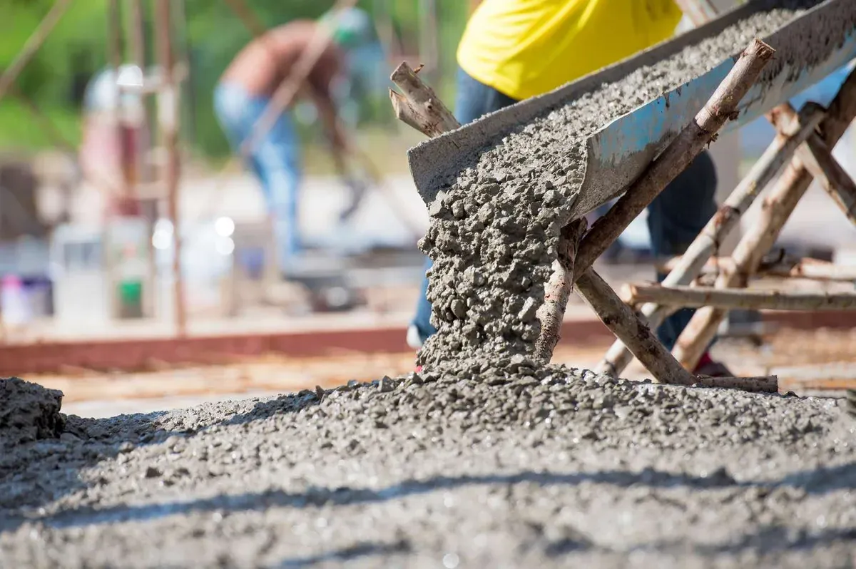 A chute discharging fresh concrete onto a slab as the crew works it in — concrete contractor insurance in Connecticut