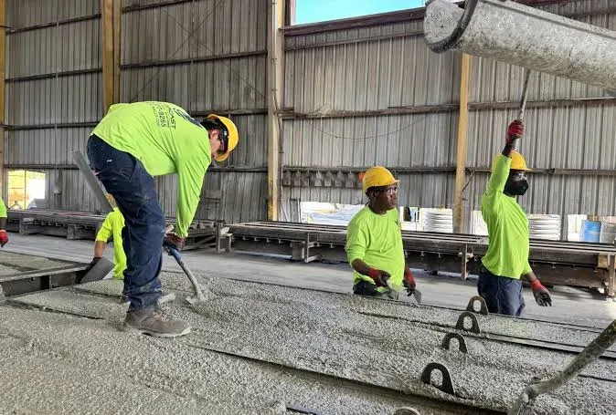 A crew troweling and finishing a concrete slab inside a metal building — concrete contractor insurance in Delaware