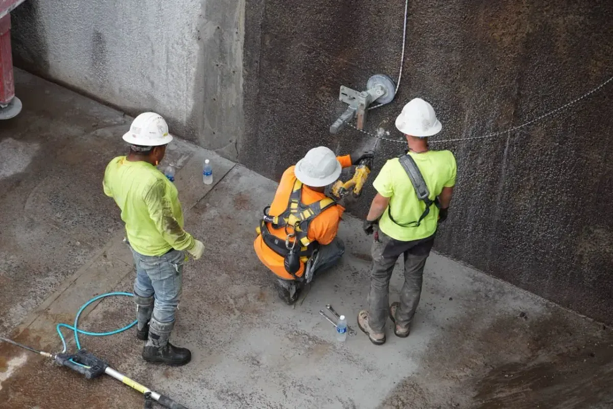 Workers core-drilling and setting anchors into a finished concrete wall — concrete business insurance