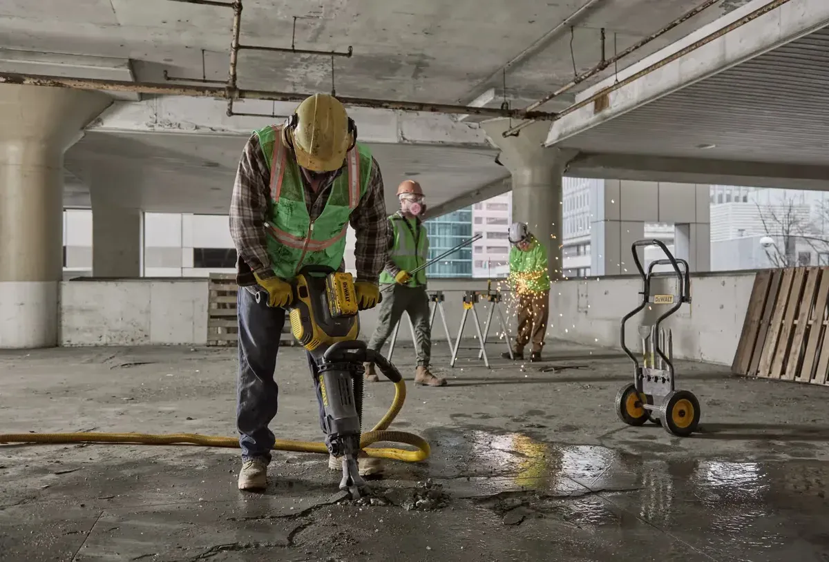 A worker breaking up a concrete floor with a demolition hammer in a parking structure — concrete business insurance