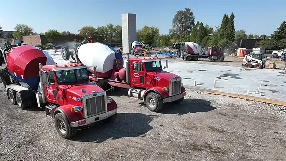 Two ready-mix mixer trucks staged at a slab jobsite with a skid steer behind them — ready-mix concrete insurance in Arkansas