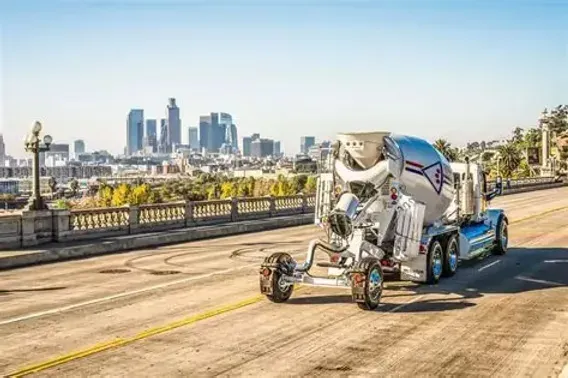 A ready-mix mixer truck with a trailing booster axle crossing a bridge — ready-mix concrete insurance in Virginia