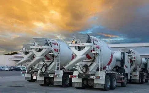 A line of ready-mix mixer trucks staged at dusk — ready-mix concrete insurance in Delaware